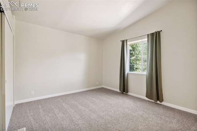 carpeted spare room with lofted ceiling