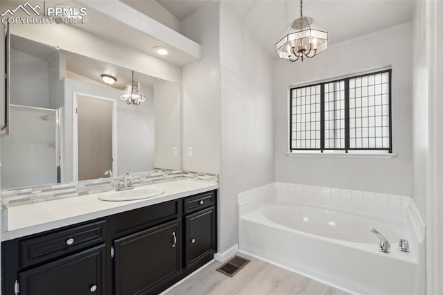 bathroom with an inviting chandelier, vanity, shower with separate bathtub, and wood-type flooring