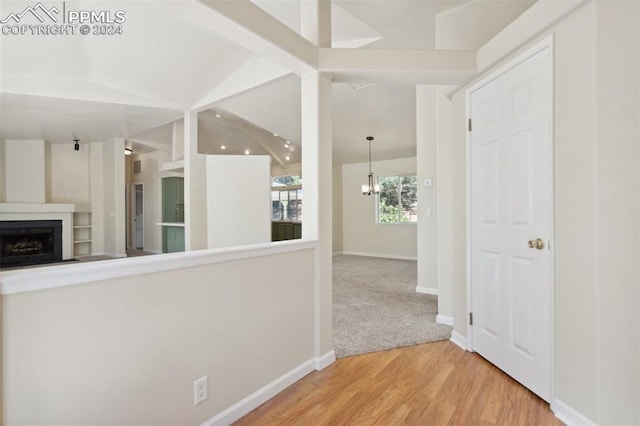 corridor featuring a notable chandelier, wood-type flooring, and lofted ceiling