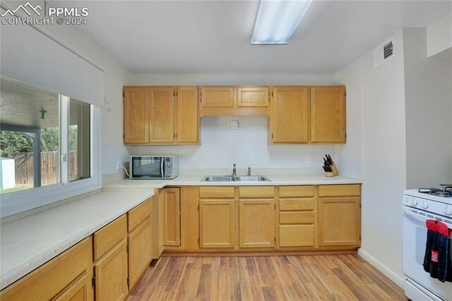 kitchen with light brown cabinets, light wood-type flooring, sink, and white range with gas cooktop