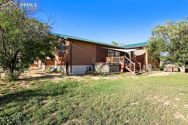 rear view of house with a lawn and a wooden deck