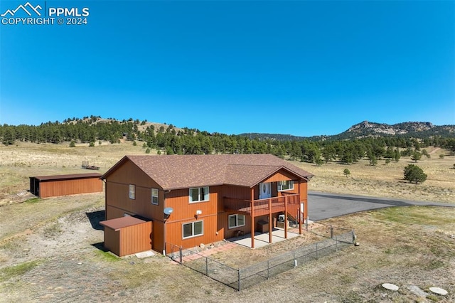 back of property with a mountain view and a rural view