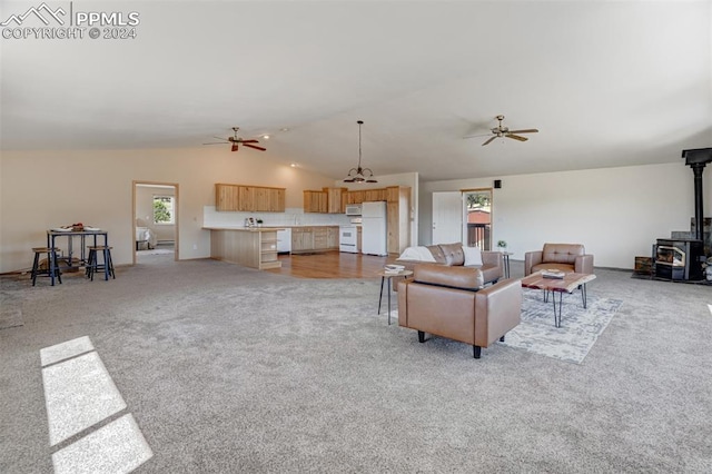 living room with vaulted ceiling, light carpet, ceiling fan, and a wood stove