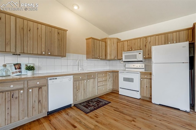 kitchen featuring white appliances, vaulted ceiling, sink, and light hardwood / wood-style flooring