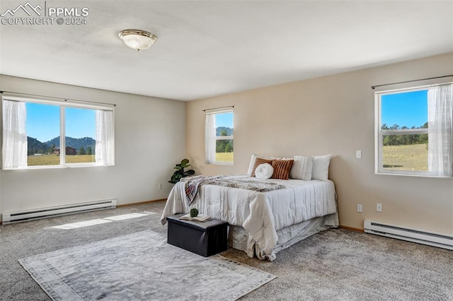 bedroom with a baseboard radiator, a mountain view, multiple windows, and light colored carpet