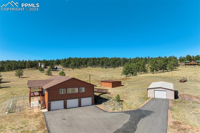 view of front of property featuring an outdoor structure, a rural view, and a garage