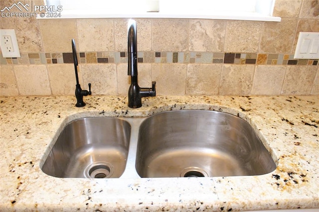 room details featuring backsplash, light stone counters, and sink