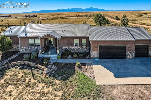 ranch-style home with a garage, a mountain view, and a rural view