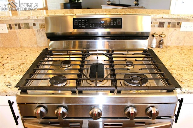 interior details featuring stainless steel range oven, light stone countertops, and tasteful backsplash