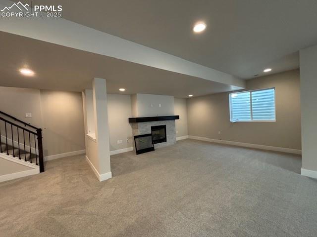 below grade area featuring recessed lighting, carpet floors, a fireplace, baseboards, and stairs