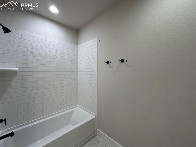 bathroom featuring marble finish floor, baseboards, and bathtub / shower combination