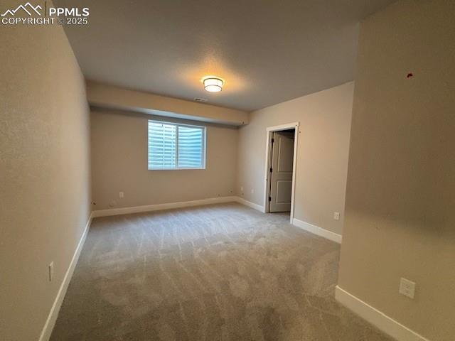 carpeted spare room featuring baseboards