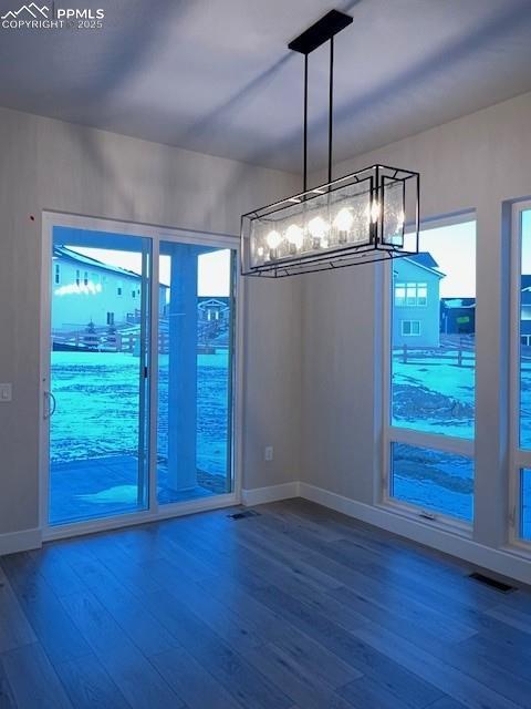 unfurnished dining area with visible vents, baseboards, and wood finished floors