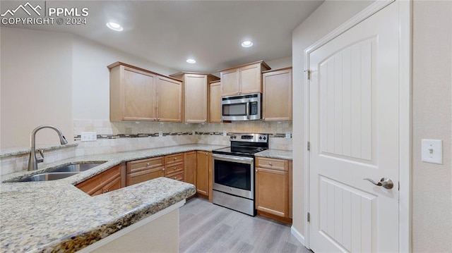 kitchen with light hardwood / wood-style floors, backsplash, light stone countertops, stainless steel appliances, and sink