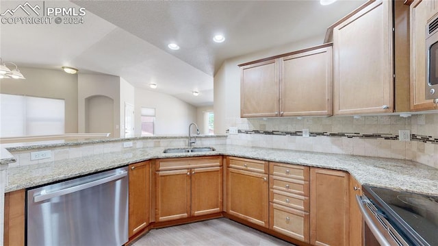 kitchen featuring vaulted ceiling, light stone counters, backsplash, stainless steel appliances, and sink