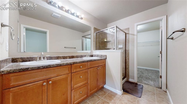 bathroom with walk in shower, vanity, and tile patterned floors