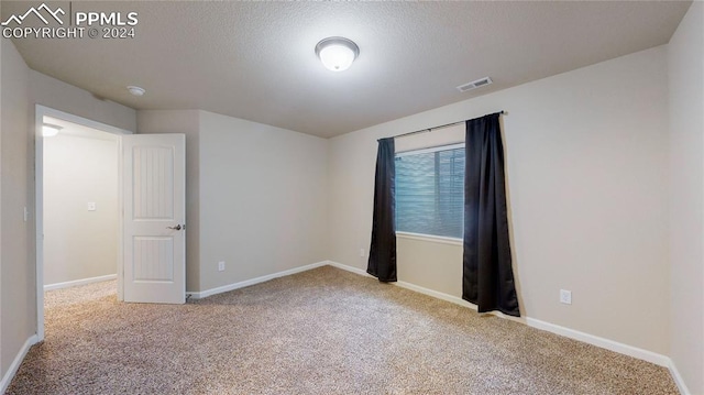 spare room with a textured ceiling and light carpet