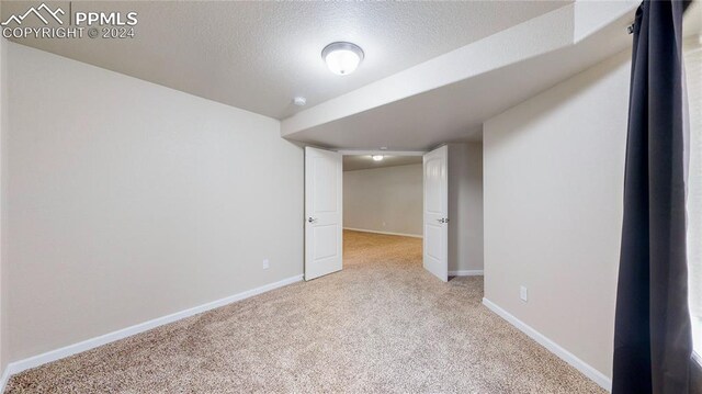 basement with a textured ceiling and light colored carpet