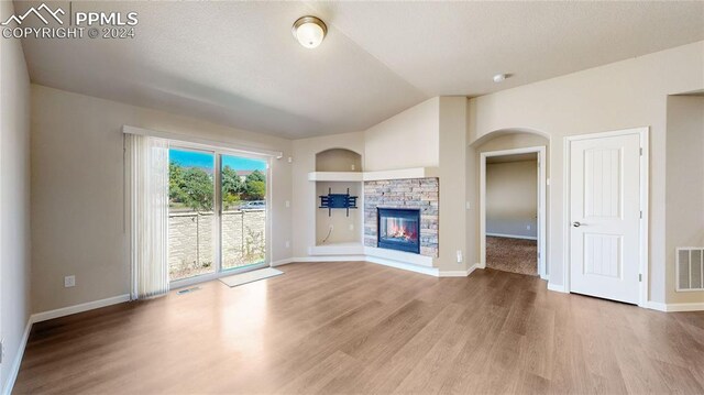 unfurnished living room with wood-type flooring, a fireplace, and vaulted ceiling