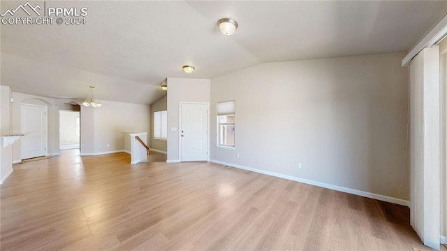 unfurnished living room with light wood-type flooring, lofted ceiling, and an inviting chandelier