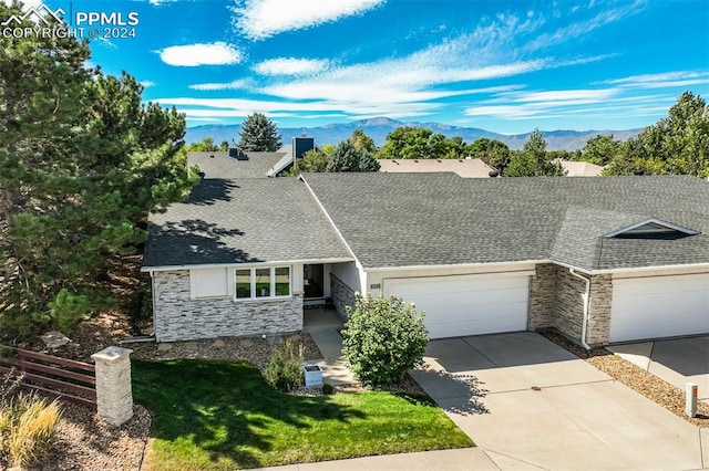 ranch-style home with a front yard, a mountain view, and a garage