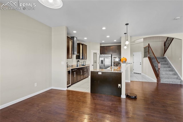 kitchen featuring light hardwood / wood-style flooring, stainless steel appliances, hanging light fixtures, and wall chimney exhaust hood