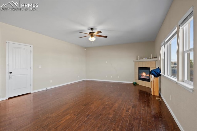 unfurnished living room with a tiled fireplace, ceiling fan, and dark hardwood / wood-style flooring