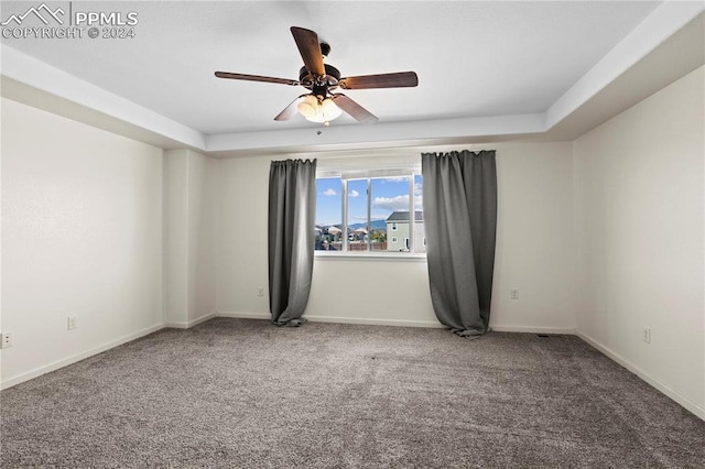 carpeted empty room with a tray ceiling and ceiling fan