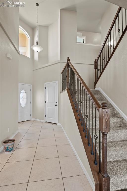 foyer entrance with tile patterned flooring, a towering ceiling, and a wealth of natural light