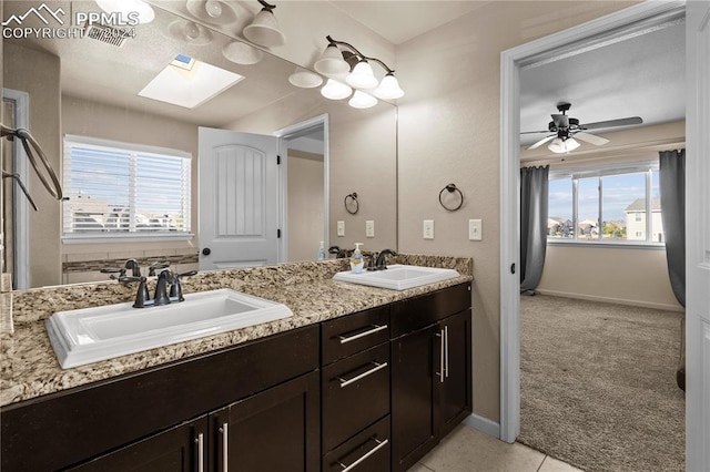 bathroom featuring vanity, ceiling fan, a skylight, and a wealth of natural light