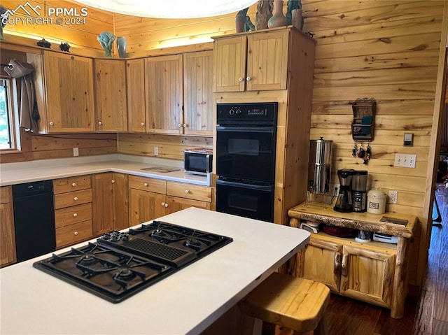 kitchen featuring a kitchen breakfast bar, black appliances, and wooden walls