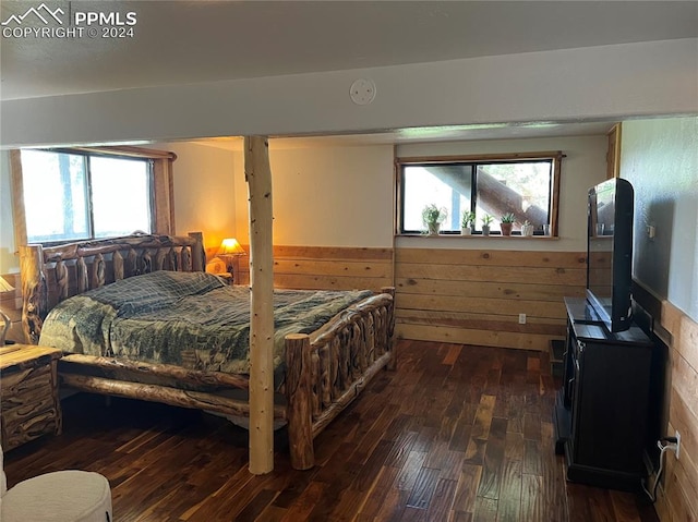 bedroom with wood walls and dark hardwood / wood-style flooring