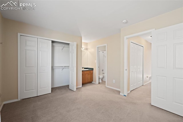 unfurnished bedroom featuring light carpet and connected bathroom