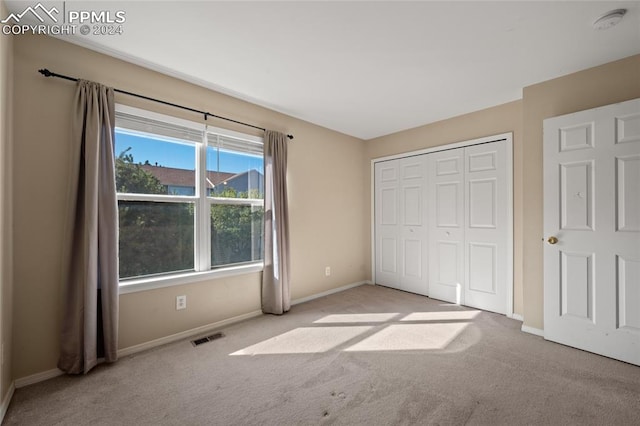 unfurnished bedroom with light colored carpet and a closet