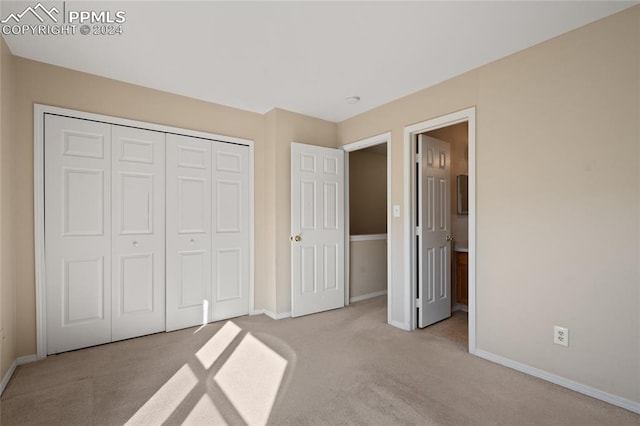 unfurnished bedroom featuring light colored carpet and a closet