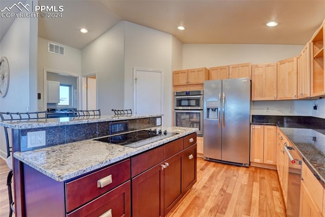 kitchen featuring a kitchen bar, a center island, light hardwood / wood-style flooring, and stainless steel appliances