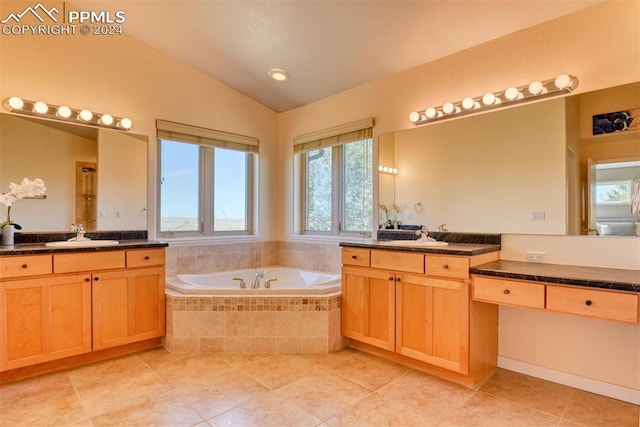 bathroom with lofted ceiling, tiled tub, plenty of natural light, and vanity