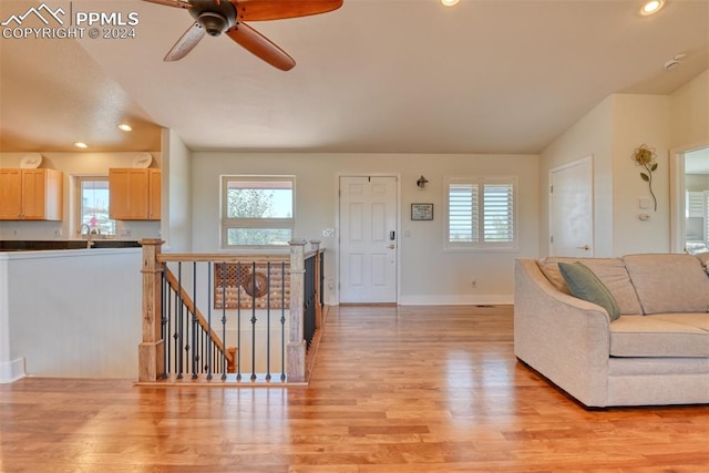 living room with ceiling fan, sink, light hardwood / wood-style flooring, and vaulted ceiling