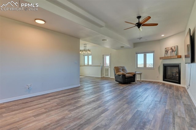 unfurnished living room featuring ceiling fan with notable chandelier and hardwood / wood-style floors