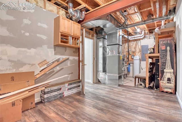 basement featuring wood-type flooring, electric panel, and heating unit