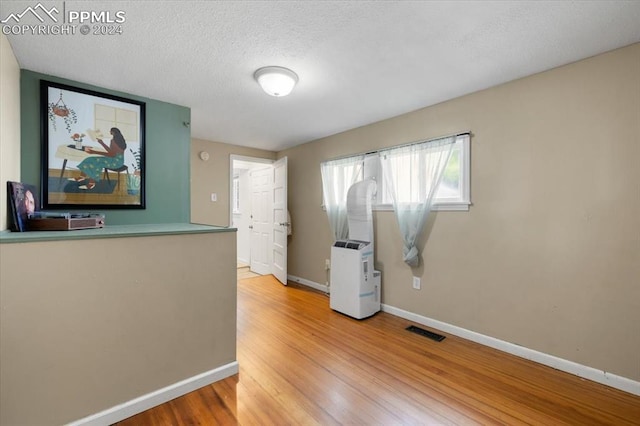 unfurnished room with hardwood / wood-style flooring and a textured ceiling