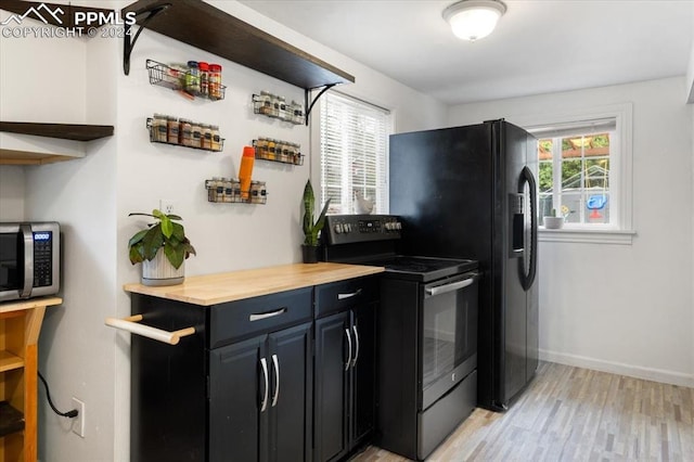 kitchen with black appliances, wood counters, and light hardwood / wood-style flooring