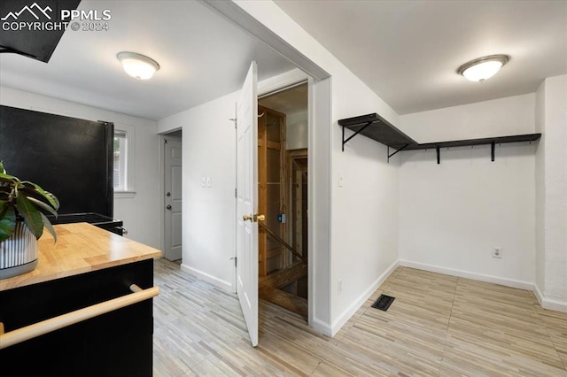 walk in closet with light hardwood / wood-style floors