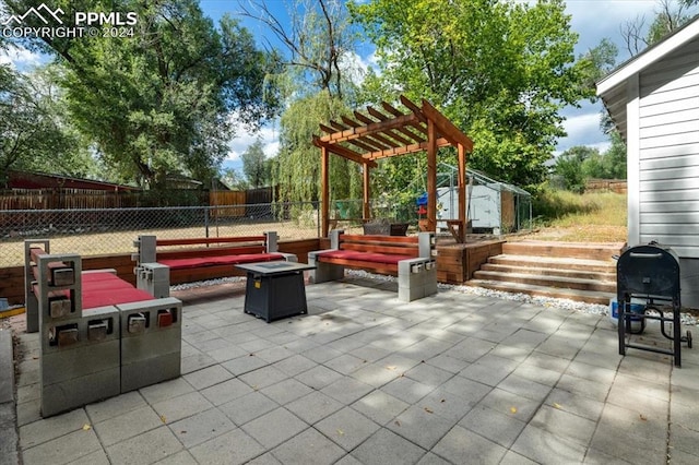 view of patio with a storage shed, a pergola, and a fire pit