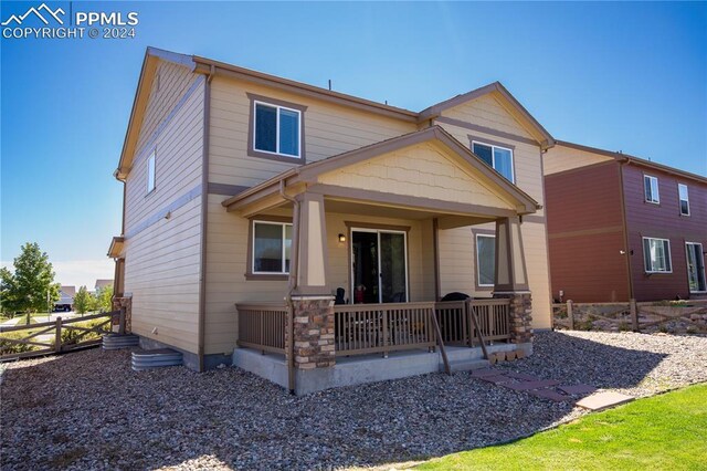 6777 Ironwood Tree Cir, Colorado Springs, CO 80927 - rear view of house with covered porch, fence, and stone siding