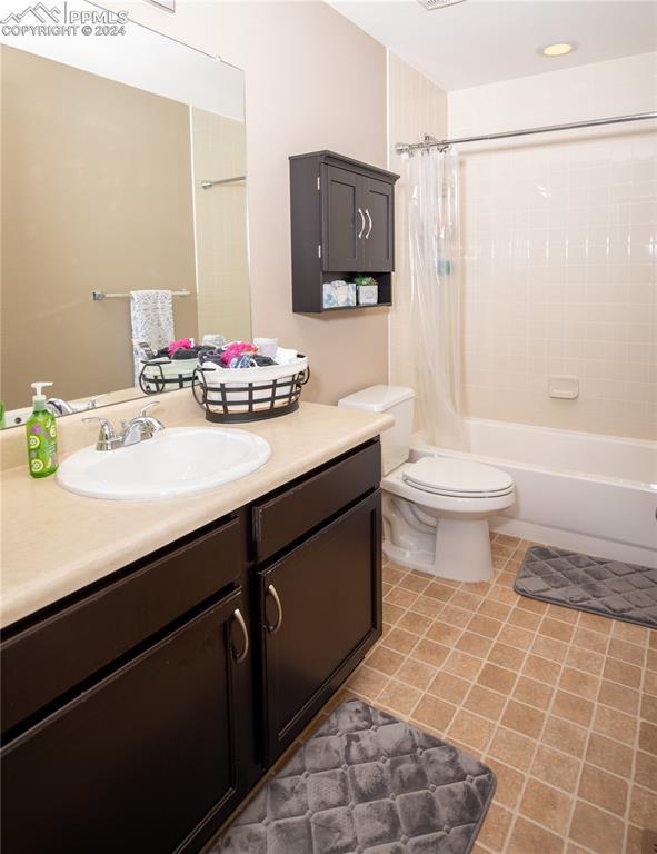 6777 Ironwood Tree Cir, Colorado Springs, CO 80927 - bathroom featuring vanity, shower / tub combo with curtain, tile patterned floors, and toilet