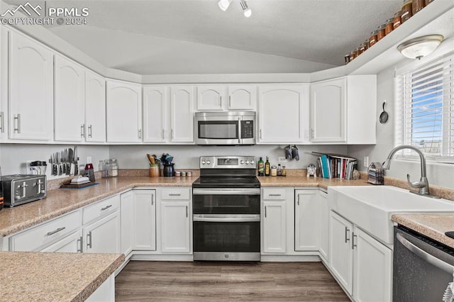 kitchen featuring lofted ceiling, sink, white cabinetry, stainless steel appliances, and dark hardwood / wood-style flooring