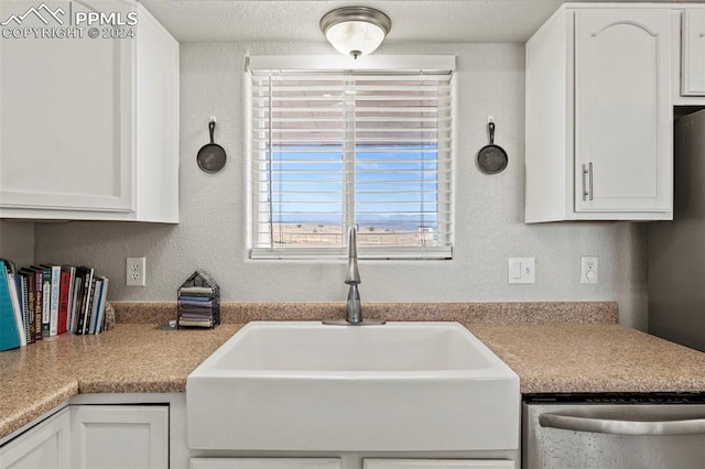 kitchen with stainless steel dishwasher, white cabinetry, a textured ceiling, and sink