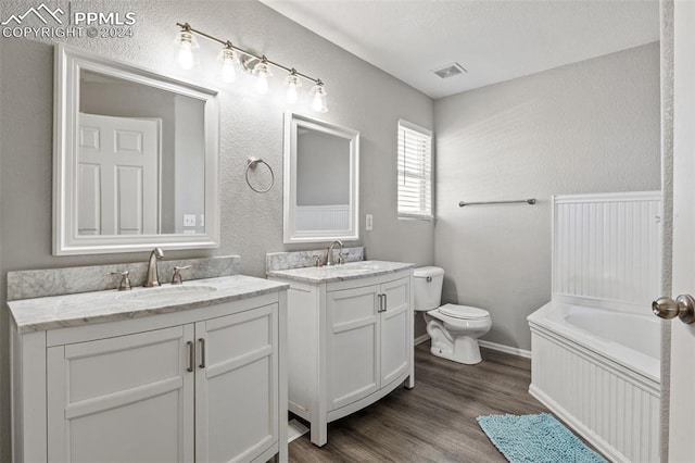 bathroom featuring wood-type flooring, a washtub, vanity, and toilet