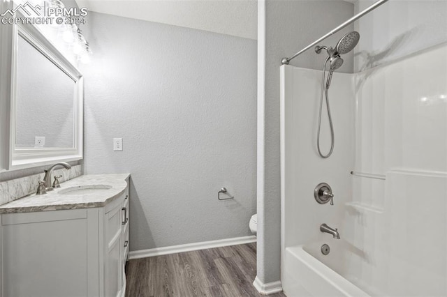 full bathroom featuring hardwood / wood-style floors, vanity, toilet, and bathing tub / shower combination